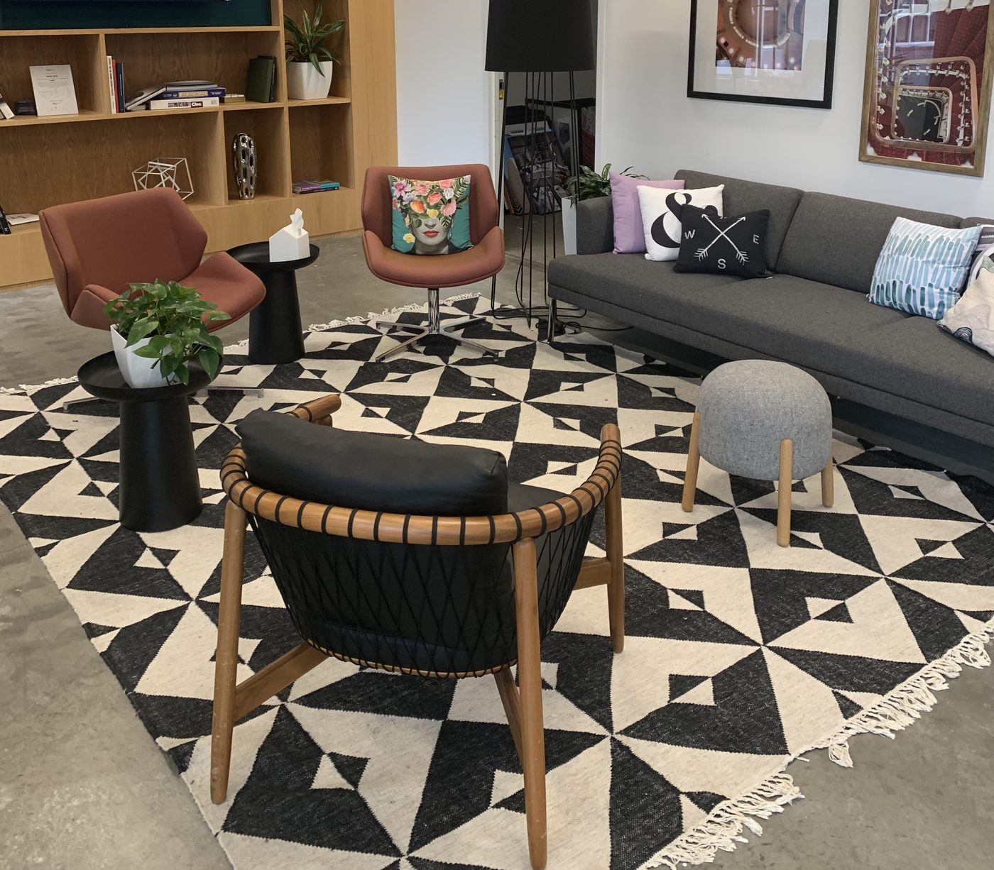 The waiting area inside the Bakery Square office — bookshelves, cognac swivel chairs, charcoal sofa, and a black-and-cream geometric rug